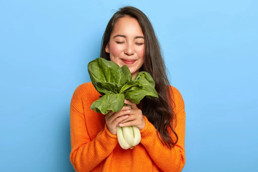 Mujer con verduras frescas disfrutando de una dieta vegana equilibrada